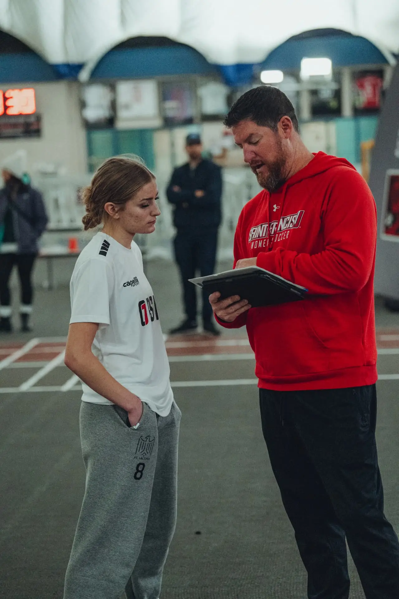 A college coach reviewing a player's profile with her at an OPSM event