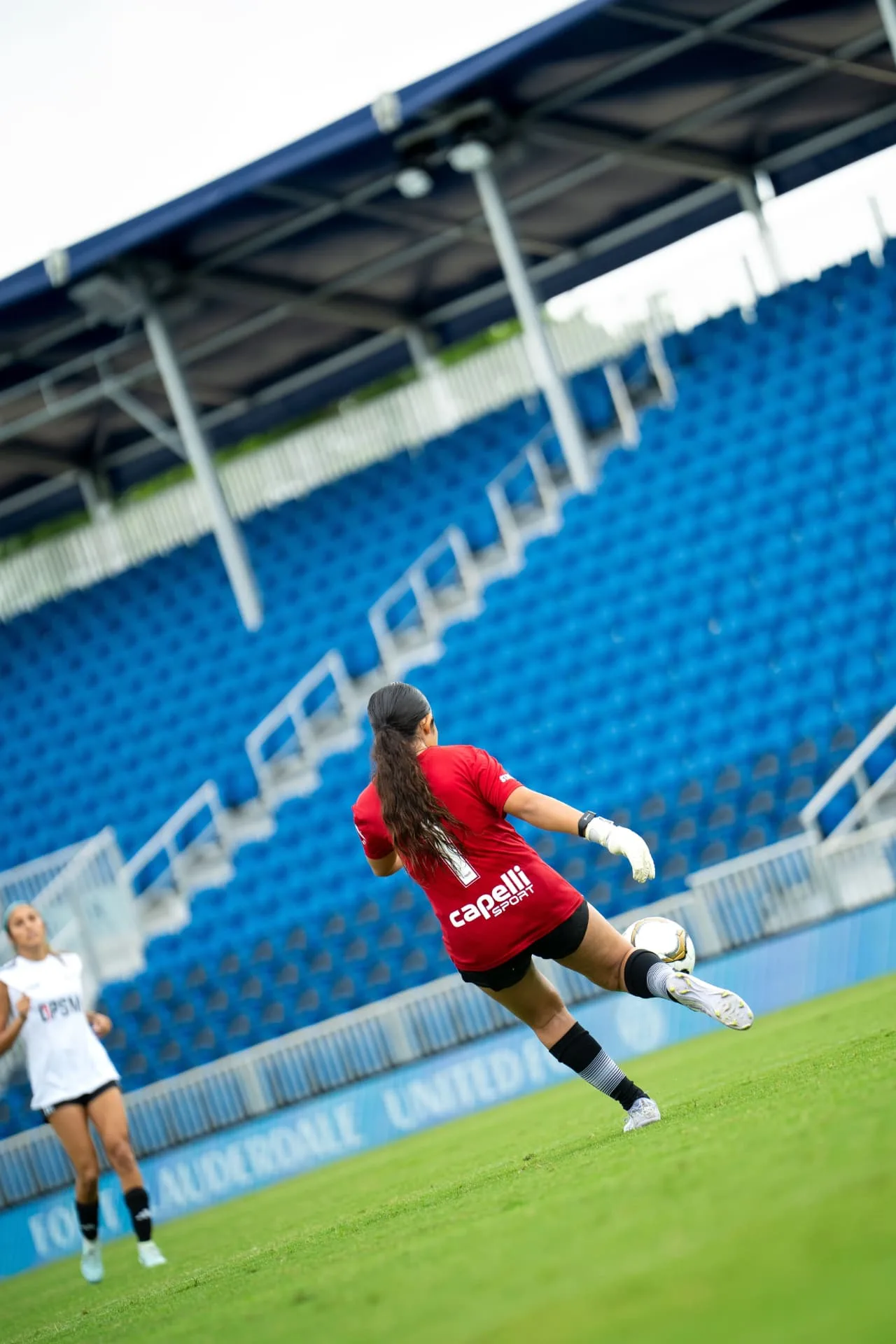 Goalkeeper in red striking a goal kick downfield