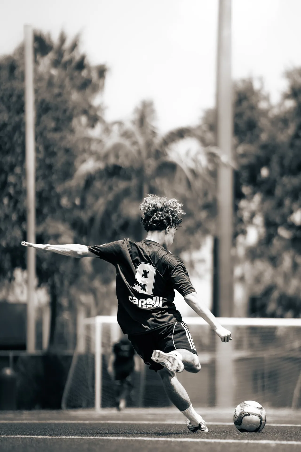 Player in number nine kit striking a pass