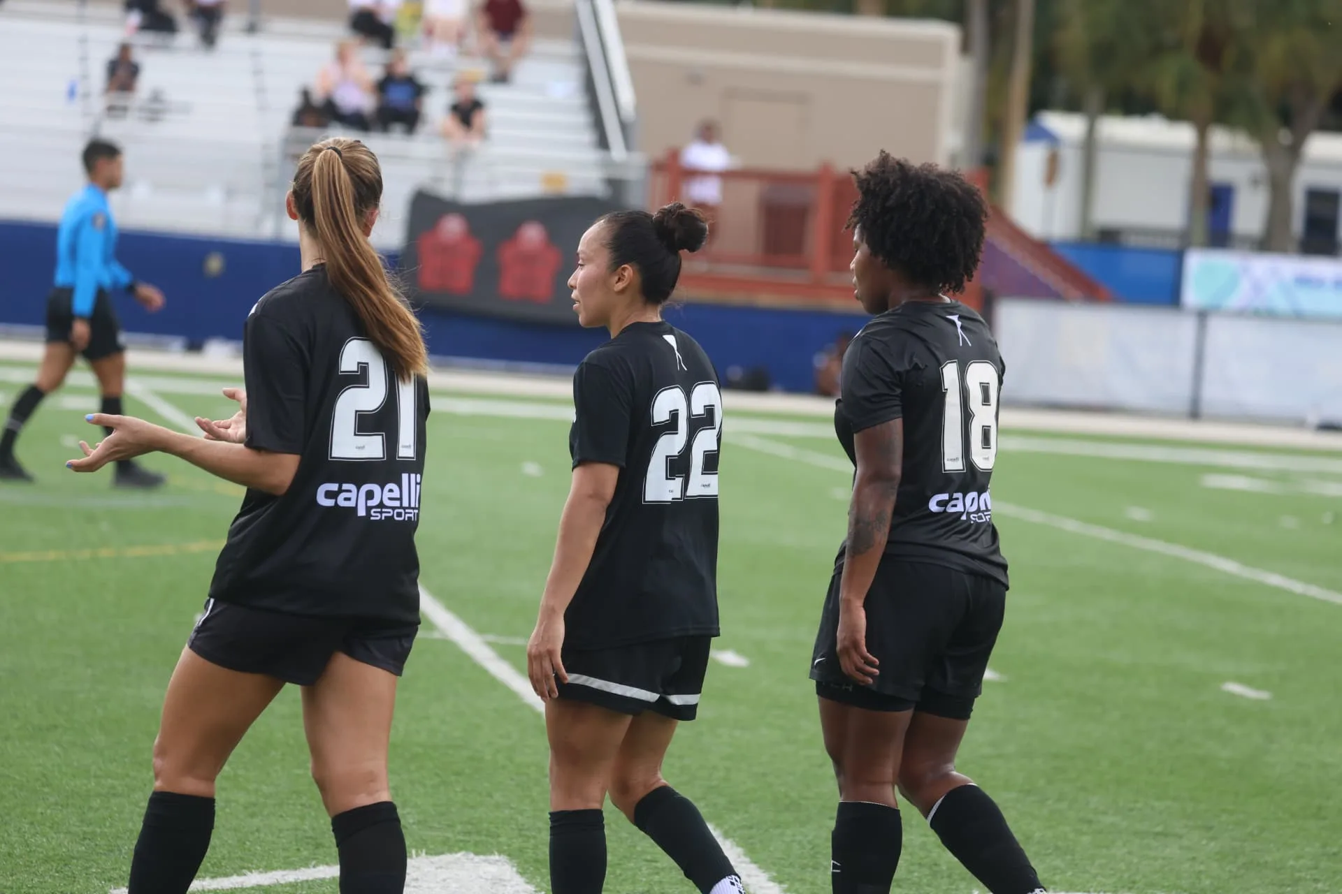 Three players in black kits regrouping during the match