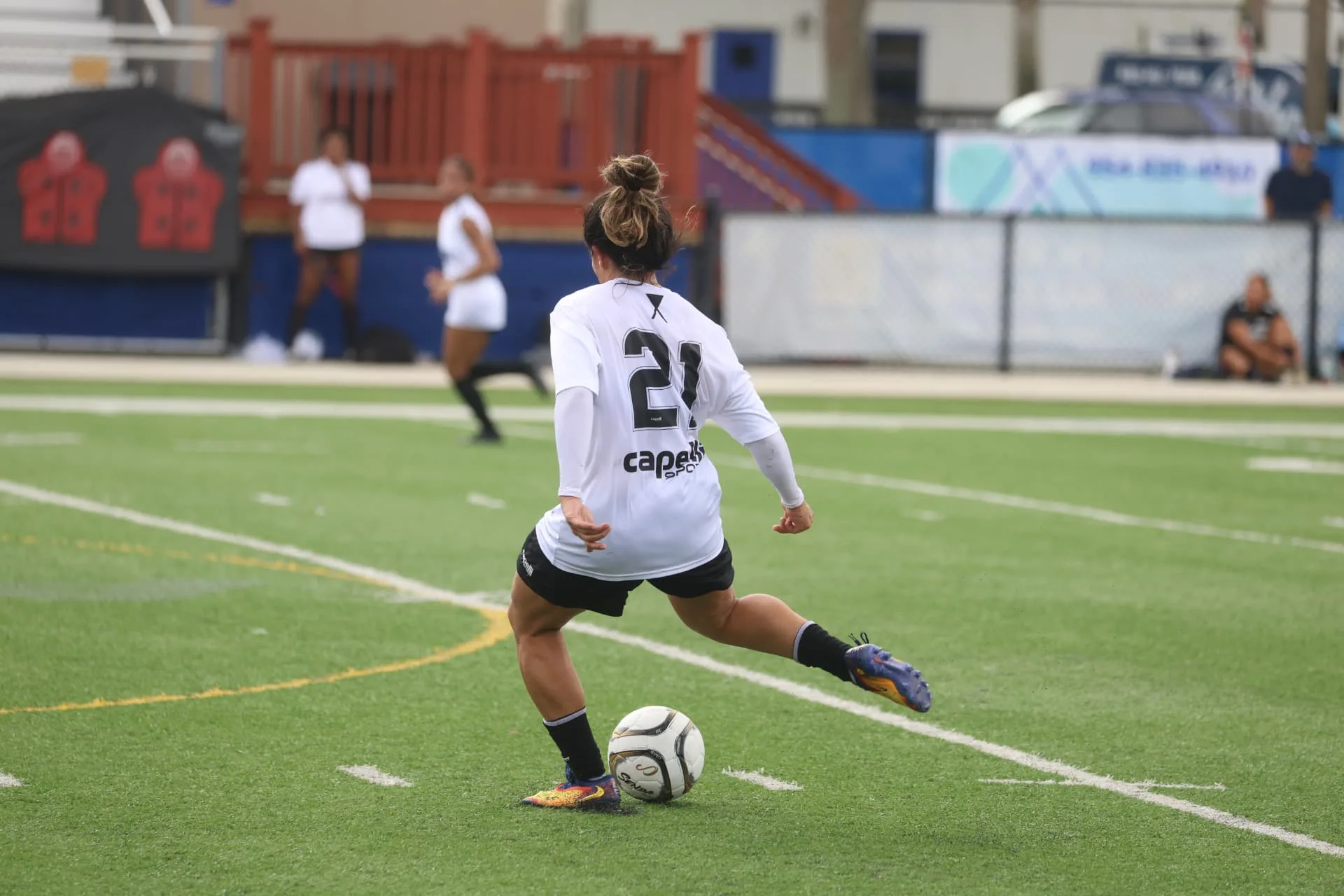 Player striking a long pass in the white OPSM kit