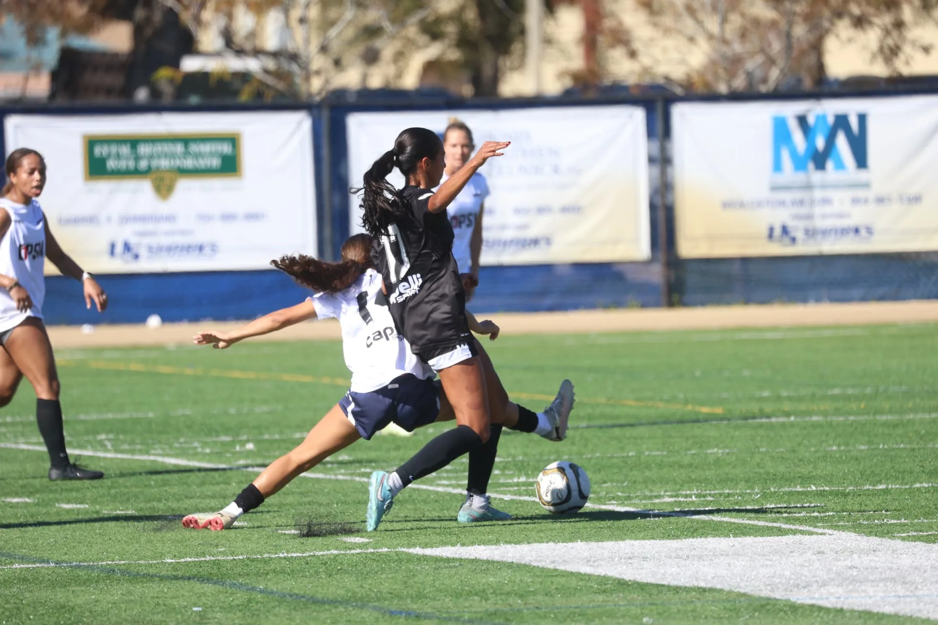 Attacker striking the ball as a defender slides in