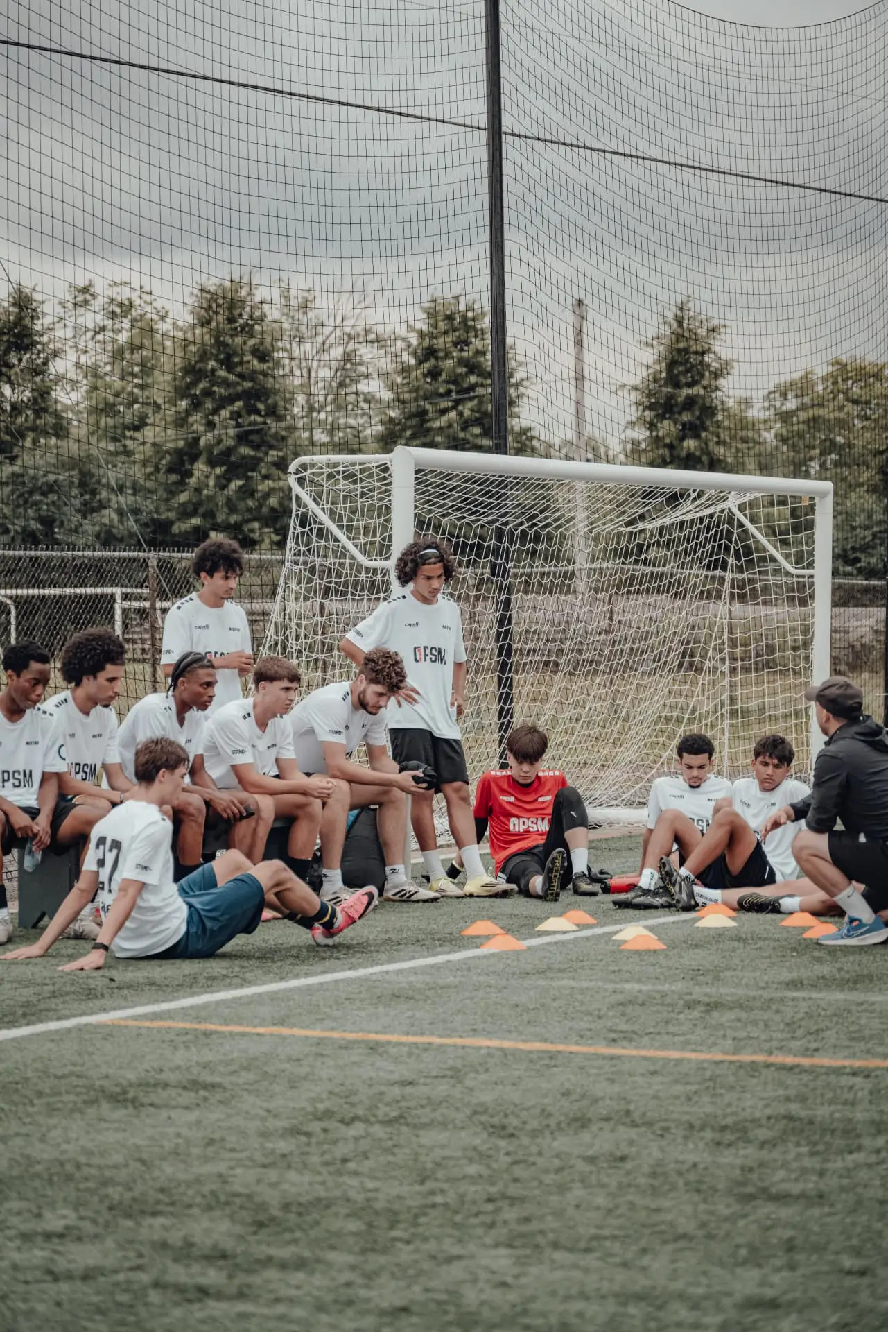 Players resting by the goal while a coach speaks to the group