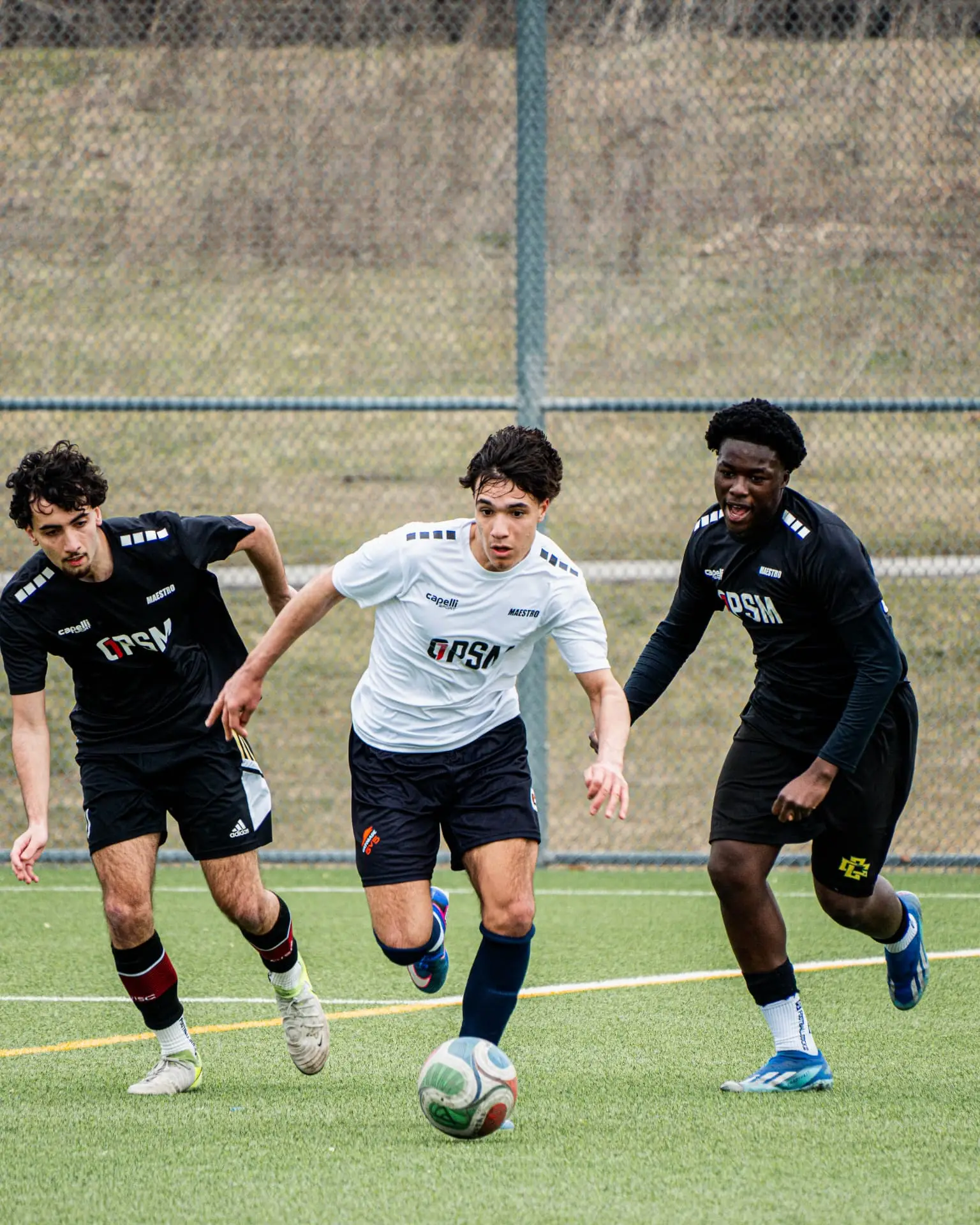 Three players competing for the ball during an 11v11 match