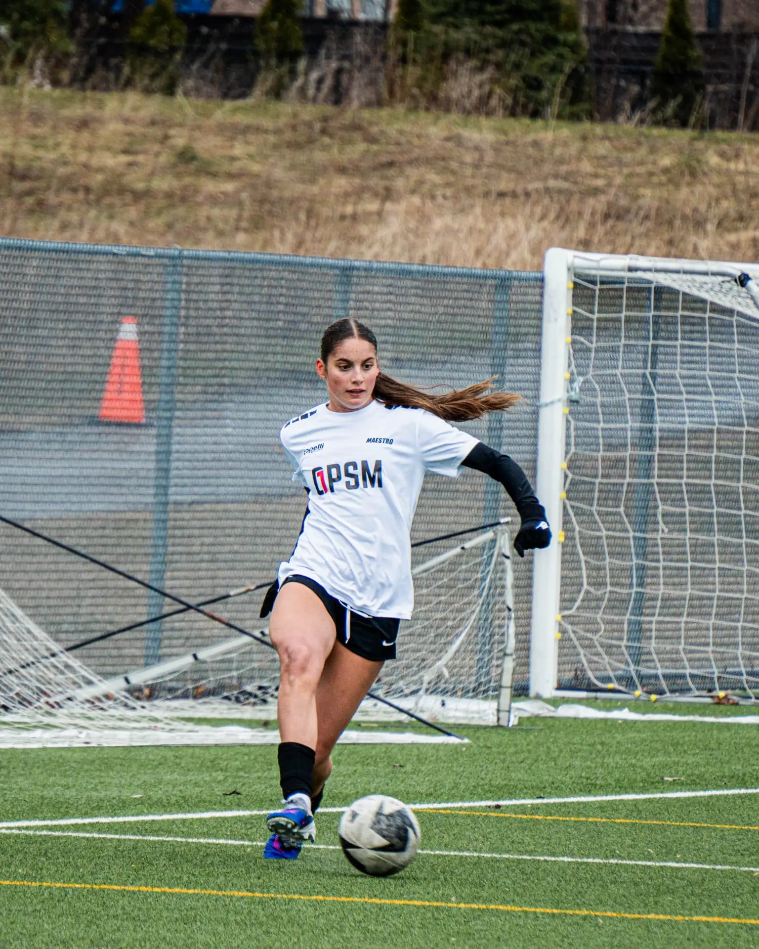 Player in OPSM white kit driving forward with the ball